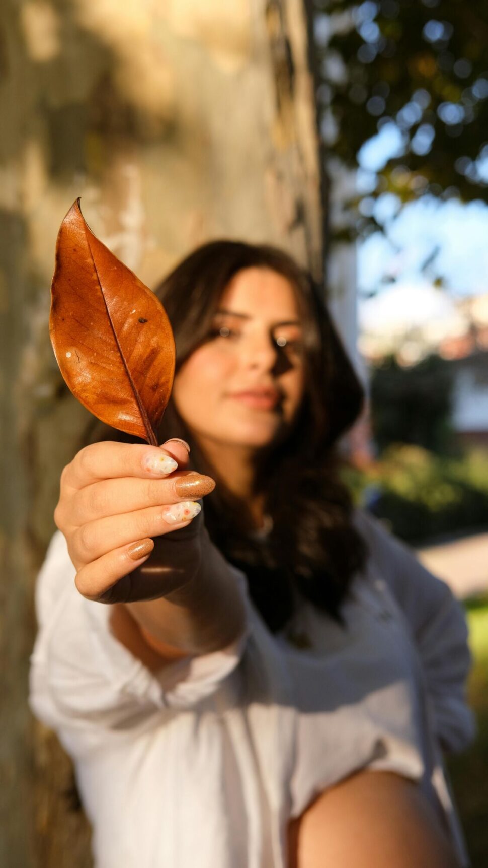 https://www.pexels.com/photo/woman-holding-autumn-leaf-in-sunny-outdoor-setting-29444971/