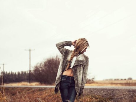 https://www.pexels.com/photo/photo-of-woman-in-a-gray-sweater-white-tank-top-and-blue-jeans-standing-on-the-side-of-the-road-posing-while-looking-away-2495794/