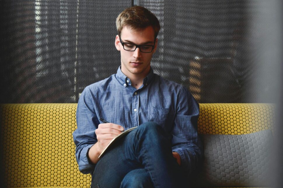 https://www.pexels.com/photo/person-in-blue-denim-jacket-sitting-on-chair-while-writing-39866/